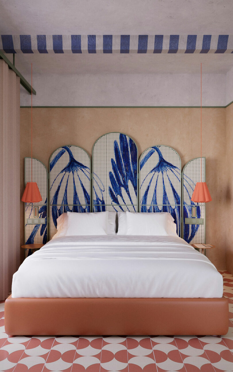 A bed with white bedding stands against a decorative headboard with blue abstract designs; pink lamps hang on either side, and the floor has a geometric pink and white pattern.
