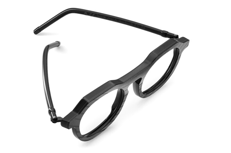 Round black eyeglass frames with thick rims, lying open on a white background.