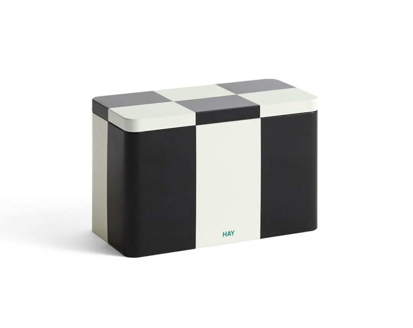Rectangular metal storage tin with a black, white, and grey checkered lid and a white vertical stripe on the front; "HAY" printed in green near the base. A stylish pick for any 2025 Gift Guide.