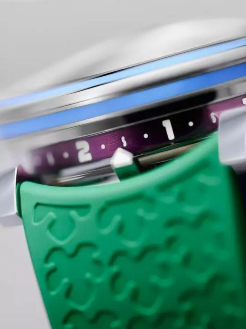 Close-up of a wristwatch showing a purple rotating bezel with numbers and a green textured strap