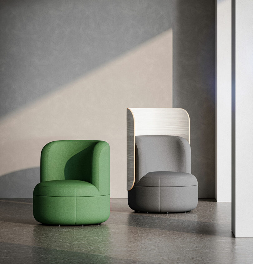 Two modern, rounded lounge chairs sit in a sunlit room; one is green and the other is gray with a tall, curved wooden backrest.