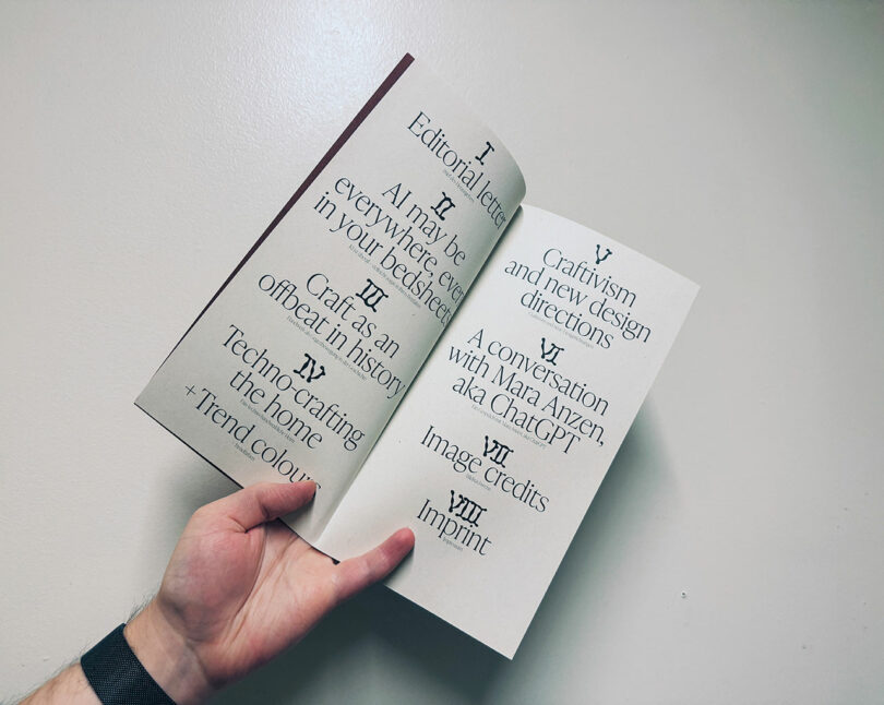 A hand holds open a booklet to its table of contents, listing eight sections in Roman numerals on two cream-colored pages with serif fonts.