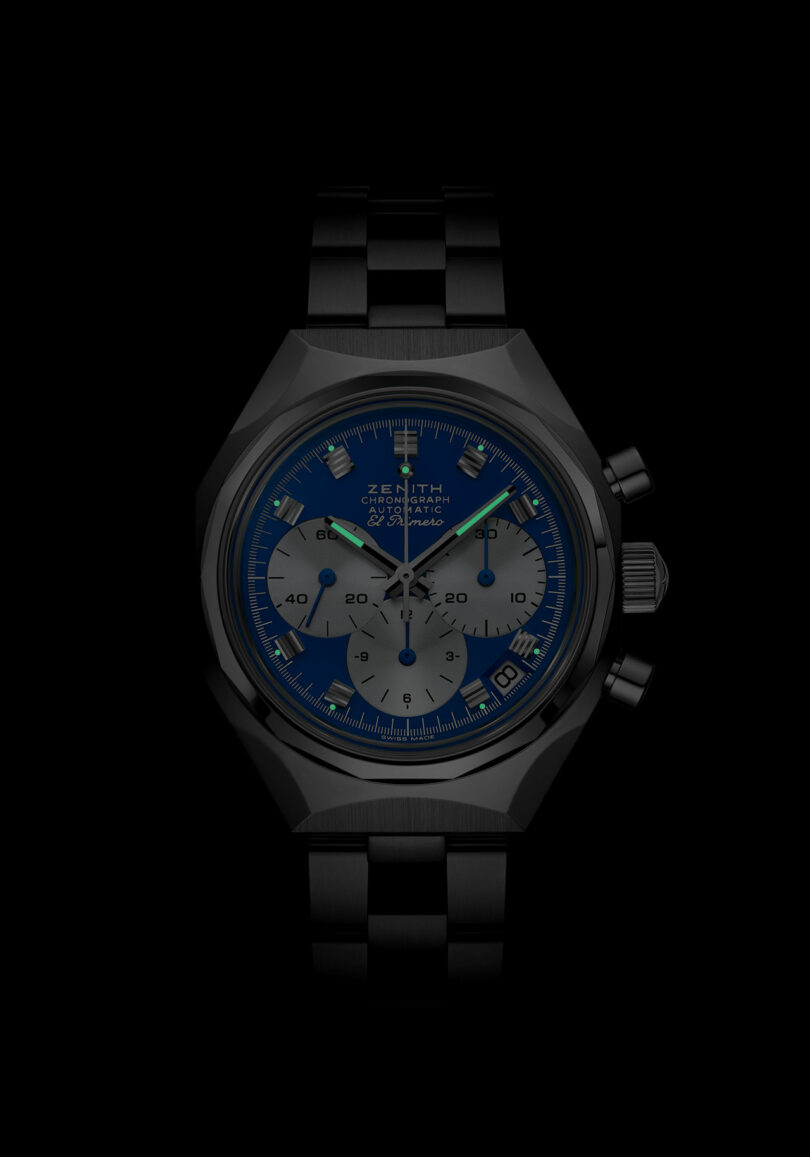 A black metal wristwatch with a blue dial, three subdials, and luminous markers, displayed against a black background.