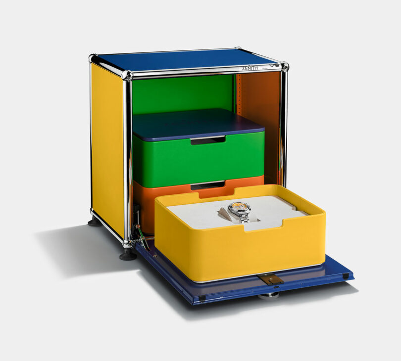 A colorful storage cabinet with open drawers in yellow, green, and orange; the front yellow drawer displays a watch inside.