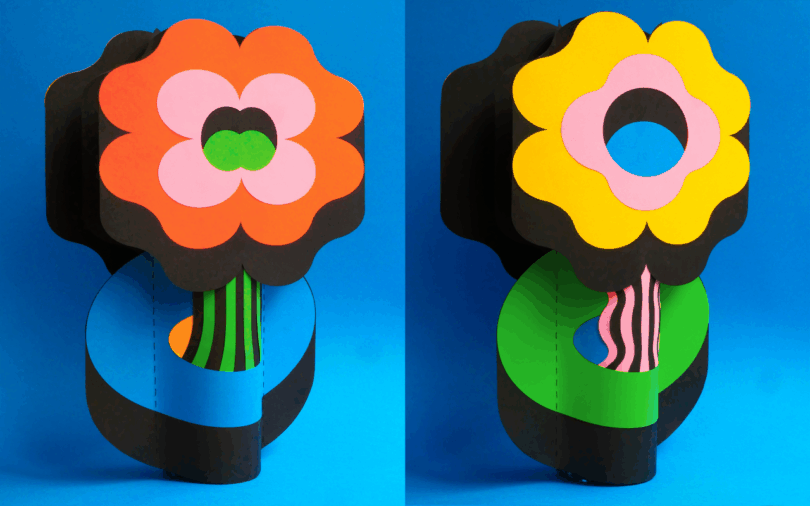 Two colorful, stylized paper flowers with bold shapes and patterns are displayed side by side against a bright blue background